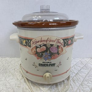 Puede incluir: Olla de cocción lenta de gres Rival Crock-Pot de color crema con tapa de cristal transparente y borde marrón. El diseño incluye una pancarta con el texto "A Garden of Good Things" e ilustraciones de frutas y flores. Tiene un dial de tres posiciones.