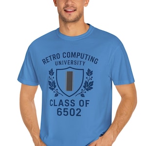 May include: A light blue t-shirt with the text "Retro Computing University" and "Class of 6502" in a dark blue design. The design includes a shield and laurel leaves.
