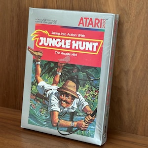 Vintage Atari 2600 Jungle Hunt video game cartridge in original shrink-wrapped silver box, CIB, NOS, retro gaming, Atari VCS