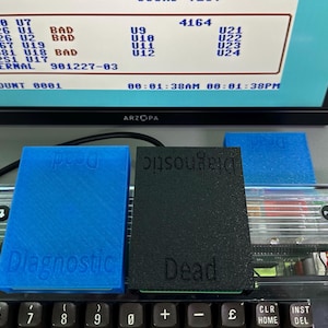 May include: A blue and black diagnostic tool set on a keyboard. The blue tool is labeled "Diagnostic" and the black tool is labeled "Dead". A computer monitor displays test results.