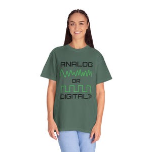 May include: Green t-shirt with the text "ANALOG OR DIGITAL?" in black. The shirt features green wave graphics representing analog and digital signals. A casual, comfortable tee for tech enthusiasts.