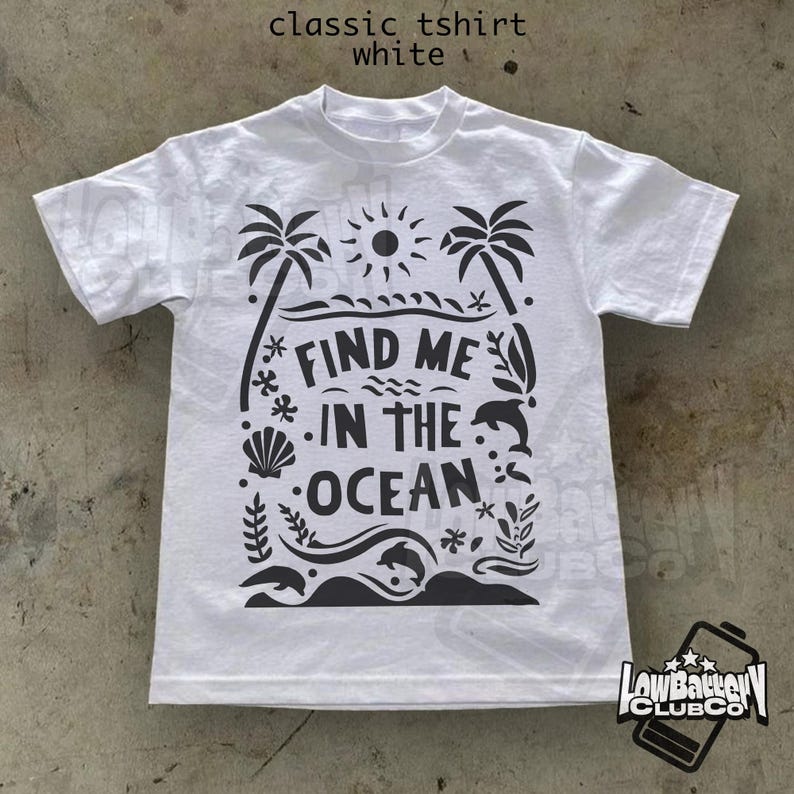 Puede incluir: Camiseta blanca cl&aacute;sica con un dise&ntilde;o gr&aacute;fico negro. El dise&ntilde;o incluye palmeras, un sol, olas, delfines y el texto "FIND ME IN THE OCEAN". La camiseta tambi&eacute;n tiene el texto "classic tshirt white" en la parte superior.