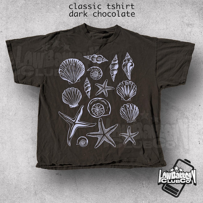 May include: Dark chocolate-colored classic t-shirt featuring a white illustration of various seashells and starfish. The shirt has short sleeves and a crew neck. The text "classic tshirt dark chocolate" is at the top.