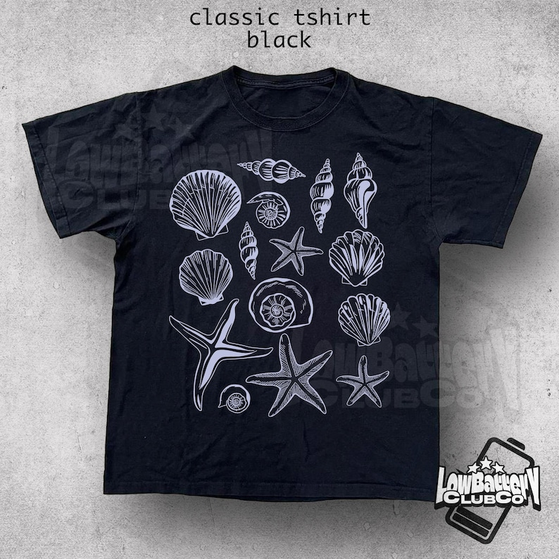 May include: Black classic t-shirt featuring a white illustration of various seashells and starfish. The shirt has the text "classic tshirt black" at the top. A logo is visible at the bottom right.
