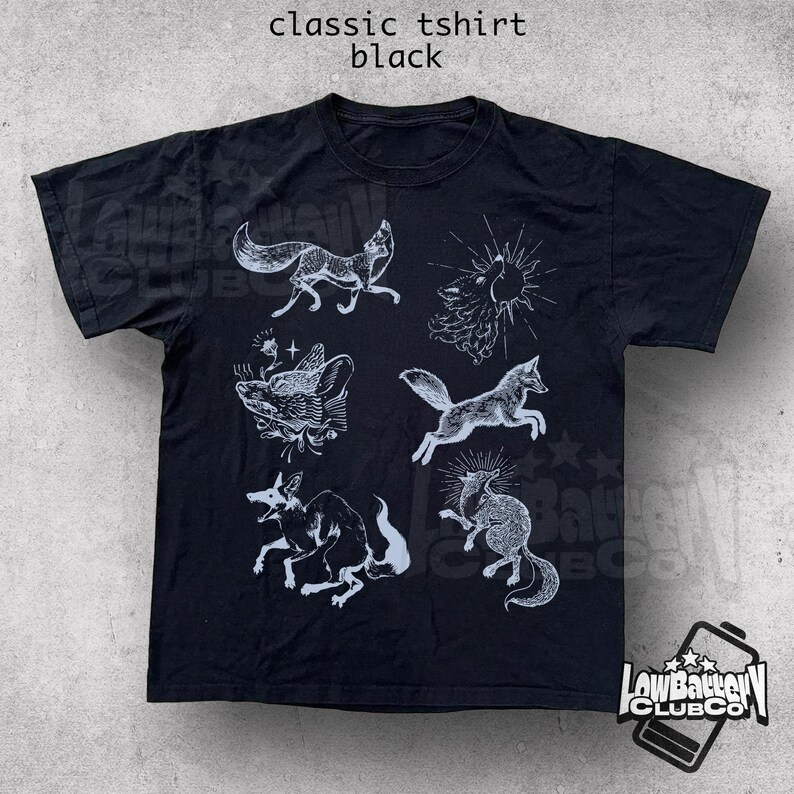 May include: Black classic t-shirt with white illustrations of foxes and other creatures. The shirt has a crew neck and short sleeves. The text "classic tshirt black" is at the top of the image.