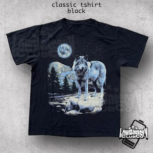 May include: Black t-shirt with a graphic of a wolf howling at the moon in a starry night sky.