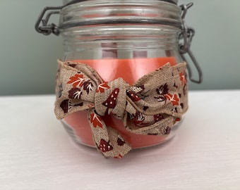 Vela Hermes de 340 ml con aroma a calabaza y especias, en frasco con bisagra y cinta.