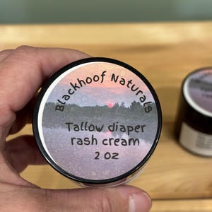 Può includere: Una tazza di ceramica bianca con manico nero e la scritta "But First, Coffee" in grassetto nero. La tazza è posta su uno sfondo sfocato, suggerendo un'atmosfera accogliente.