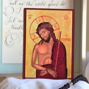 Può includere: Un'icona raffigurante una figura religiosa con una corona di spine, che tiene un bastone. La figura è vestita con abiti rossi e dorati. Lo sfondo è dorato con accenti rossi. Il testo "Peace I leave with you" è visibile sullo sfondo.
