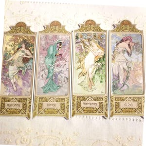 May include: A set of four decorative panels with Art Nouveau illustrations of women representing the seasons. Each panel has a gold border and the season's name in French: Automne, Hiver, Printemps, and Été.