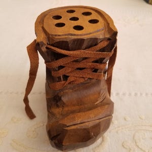 May include: A white ceramic mug with a black handle and the text "But First, Coffee" in a bold, black font. The mug is set against a blurred background, suggesting a cosy setting.