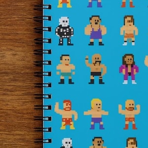 May include: A spiral-bound notebook with a repeating pattern of pixelated wrestlers on a light blue background. The wrestlers are in various poses and outfits, with a retro video game aesthetic. The notebook has a black spiral binding.