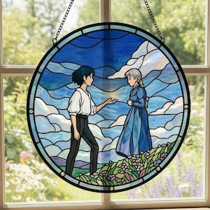 May include: Round stained glass window art featuring a scene with two figures in a blue sky and cloud background. The artwork is framed in black and suspended by a chain. The image casts a circular shadow on the floor.