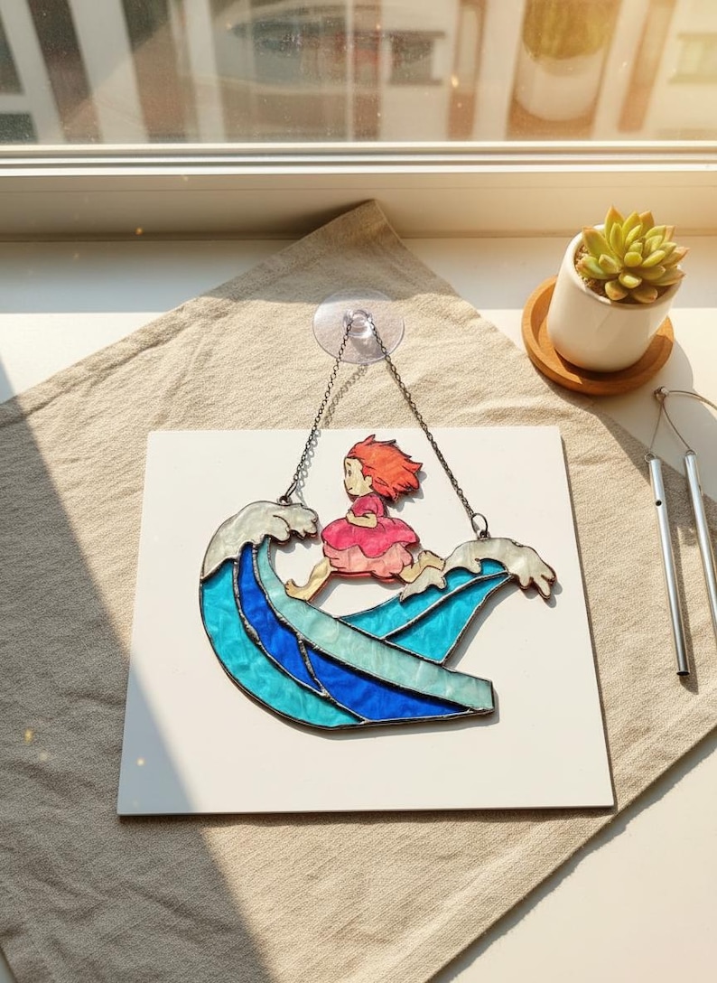 May include: Stained glass art piece depicting a girl riding a wave. The wave is composed of shades of blue and white glass. The girl is wearing a pink dress and has red hair. The piece is suspended by a chain.
