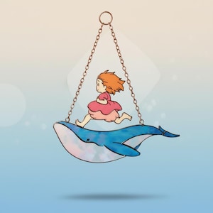 May include: A whimsical suncatcher featuring a cartoon girl in a pink dress running on a blue whale. The whale is suspended by a chain. The suncatcher has a pearlescent effect and is set against a gradient blue background.
