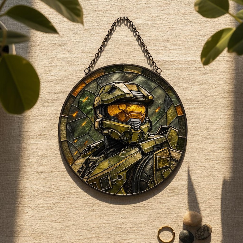 May include: Circular stained glass artwork depicting a character in green and gold armour and helmet. The piece is framed and hangs from a chain. The background features green and orange hues, creating a striking visual.