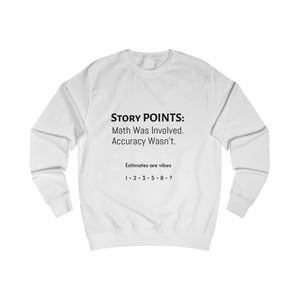 May include: White sweatshirt featuring the text "STORY POINTS: Math Was Involved. Accuracy Wasn't. Estimates are vibes 1·2·3·5·8·?" in black. A relaxed-fit, crew-neck top.