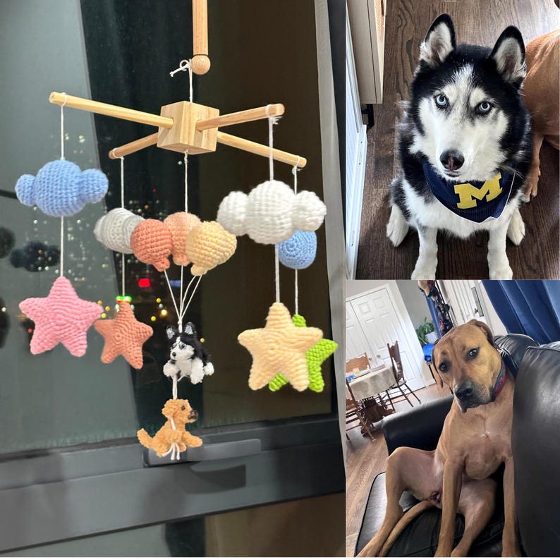 May include: A wooden mobile featuring crocheted clouds, stars, and two small dog figures hanging from white strings. The mobile includes light blue, white, peach, yellow, pink, and green yarn elements suspended from a central wooden cross frame.