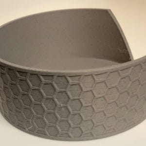 May include: A grey ceramic bowl with a hexagonal pattern. The bowl is slightly curved and has a wide opening.