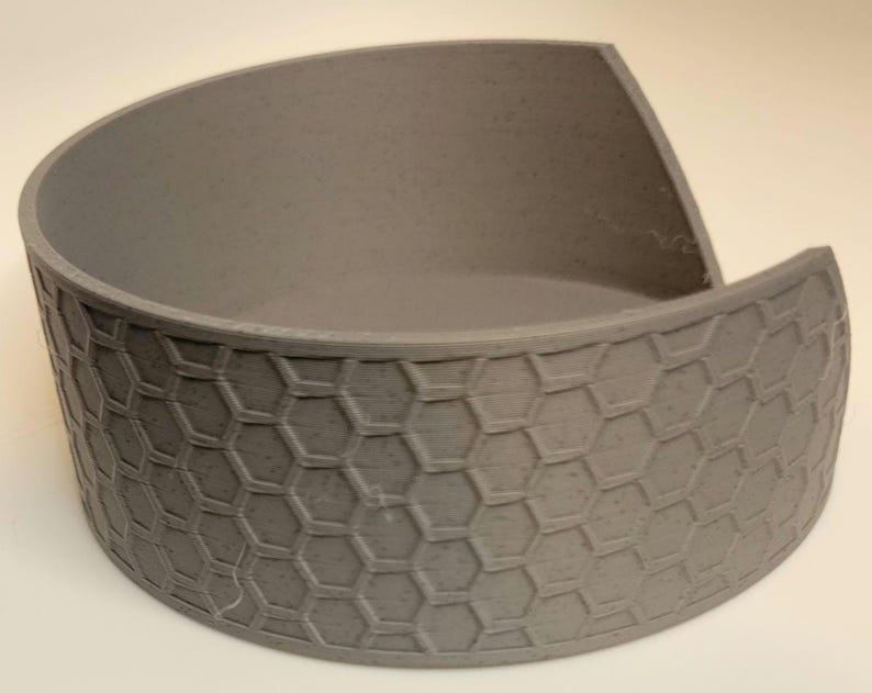 May include: A grey ceramic bowl with a hexagonal pattern. The bowl is slightly curved and has a wide opening.
