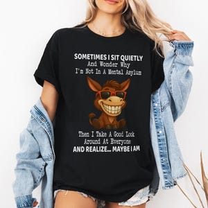 Puede incluir: Camiseta negra con el texto "SOMETIMES I SIT QUIETLY And Wonder Why I'm Not In A Mental Asylum Then I Take A Good Look Around At Everyone AND REALIZE... MAYBE I AM." La camiseta presenta un burro de dibujos animados con gafas de sol.