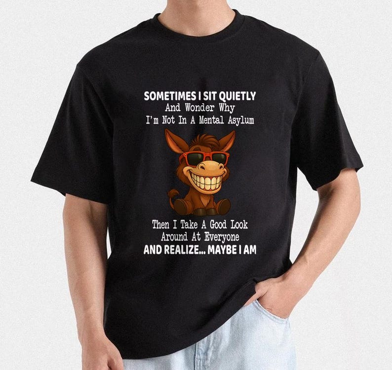 Puede incluir: Camiseta negra con un burro de dibujos animados con gafas de sol y una gran sonrisa. La camiseta tiene el texto: "SOMETIMES I SIT QUIETLY And Wonder Why I'm Not In A Mental Asylum Then I Take A Good Look Around At Everyone AND REALIZE... MAYBE I AM."