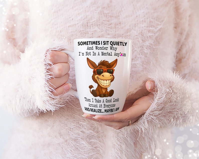 Puede incluir: Taza de cer&aacute;mica blanca con un burro de dibujos animados con gafas de sol y una gran sonrisa. La taza tiene el texto "SOMETIMES I SIT QUIETLY And Wonder Why I'm Not In A Mental Asylum Then I Take A Good Look Around At Everyone AND REALIZE... MAYBE I AM."
