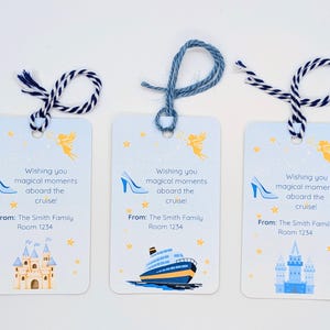 May include: Three light blue cruise tags with navy blue and white twine. Each tag has the text "Wishing you magical moments aboard the cruise!" and a high-heeled shoe, a ship, or a castle illustration. The tags also include "From: The Smith Family Room 1234."