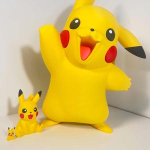 May include: A yellow Pikachu figure with red cheek circles, black-tipped ears, and a smiling expression. Two smaller Pikachu figures are also present. The large figure has an arm raised. A fun collectible for fans of the popular franchise.