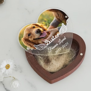 May include: A heart-shaped pet memorial box with a photo of a golden retriever. The clear lid has the name "Buster" and "Forever Loved 2013-2025" in white script. The box is brown and contains pet fur.