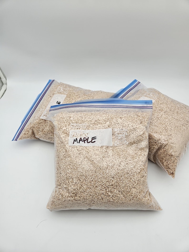 Puede incluir: Tres bolsas de pl&aacute;stico transparente llenas de virutas de madera de color marr&oacute;n claro. La bolsa de la parte delantera tiene una etiqueta blanca que dice "MAPLE" en rotulador negro. Las bolsas tienen cierres de cremallera azules y blancos.