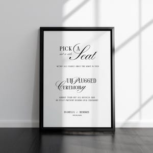 May include: A framed wedding sign with black text on a white background. The sign reads "Pick a Seat, not a side" and "Unplugged Ceremony." The names Isabella & Hendrix and the date 09.19.2028 are also displayed.