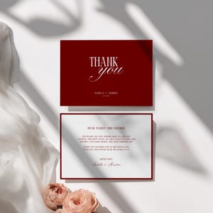 May include: A set of burgundy thank you cards with white text. The top card reads "THANK you" with a couple's names and date. The bottom card has a message to family and friends, with the couple's names at the bottom.