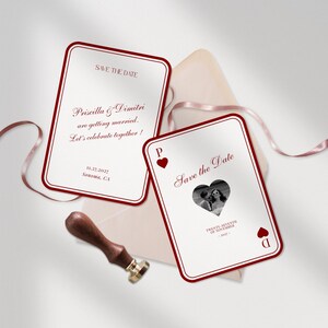 May include: Two white Save the Date cards with a red border and text. One card has a photo in a heart shape. A wooden stamp and a pink ribbon are also in the image. The cards read "Priscilla & Dimitri are getting married."