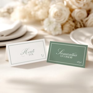 以下が含まれることがあります： 名前が書かれた2つの折り畳み式の席札。1つは白、もう1つは緑で、装飾的なボーダーが付いています。白いカードには小さな鶏のイラストとともに「Heidi Fox」と書かれています。緑色のカードには魚のイラストとともに「Samantha O'Connor」と書かれています。