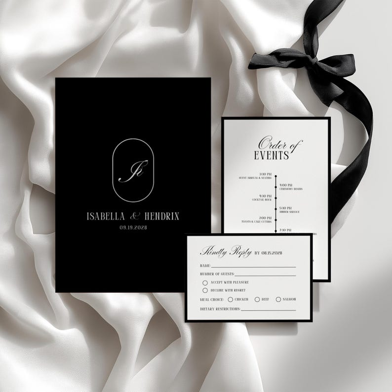 May include: Elegant black and white wedding invitation suite. Includes a main invitation with a monogram, an order of events card, and a reply card. The suite is tied with a black ribbon against a white satin background.