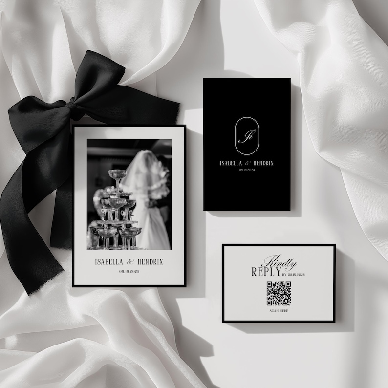 May include: A black and white wedding invitation suite featuring a framed photo of champagne glasses, a black card with a monogram, and a reply card with a QR code. The suite is accented with a black bow.