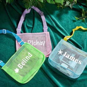 Könnte beinhalten: Drei Netztaschen in Pastellfarben: Grün, Rosa und Blau. Jede Tasche hat einen verstellbaren Riemen und einen weißen Namen auf der Vorderseite: "Belind", "Richay" und "James". Die Taschen sind zum Tragen von Gegenständen konzipiert.
