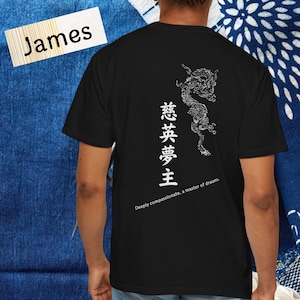 以下が含まれることがあります： 白いドラゴンデザインと日本語のテキストが特徴の黒いTシャツ。テキストは「夢のマスター」と「深く思いやりがあり、夢のマスター」と書かれています。「James」という名前の白いラベルが左上にあります。