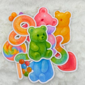 May include: A set of colourful gummy bear stickers featuring a green, blue, pink, orange, and red gummy bear. The stickers also include a rainbow lollipop, a swirl lollipop, and a donut.