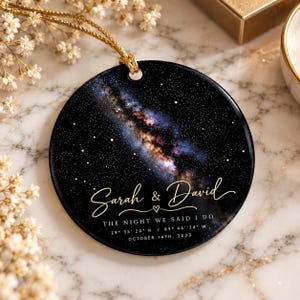 Puede incluir: Un adorno redondo de cerámica negra con un estampado de galaxia vibrante, estrellas y una nebulosa. El texto dice Sarah & David, The Night We Said I Do, 29 35 20 N / 89 44 34 W y October 14th, 2023. Incluye un cordón dorado para colgar.