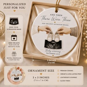 May include: A white ceramic ornament with the text "And Then There Were Three" and "Baby arriving December 2026". The ornament features an ultrasound image and baby shoes. It measures 7.6 cm in diameter.