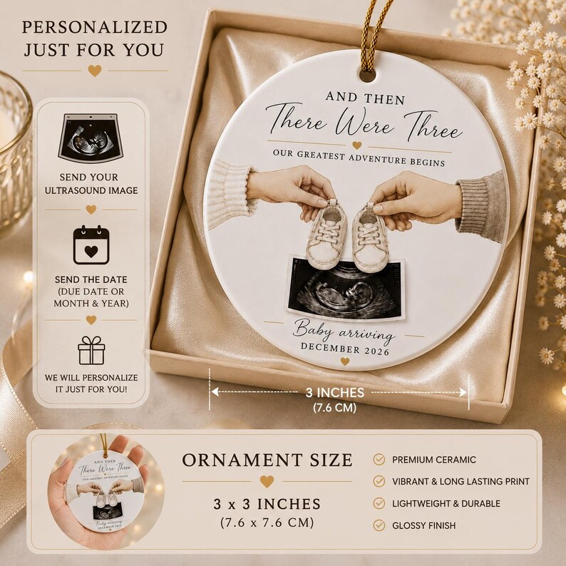 May include: A white ceramic ornament with the text "And Then There Were Three" and "Baby arriving December 2026". The ornament features an ultrasound image and baby shoes. It measures 7.6 cm in diameter.