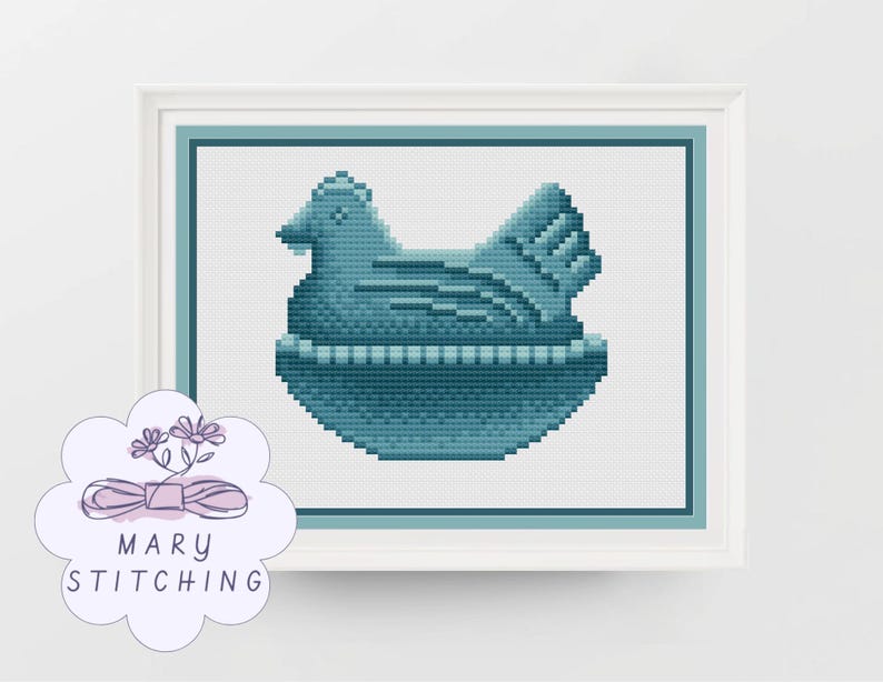 May include: A framed cross-stitch of a hen in shades of teal and blue, sitting in a nest. The artwork is displayed in a white frame with a teal border. The image includes the text "MARY STITCHING".