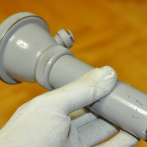 May include: A gray metal flashlight with a round head and a long, cylindrical body. The flashlight has a small, round button on the side.