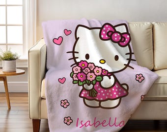 May include: A light purple blanket featuring a cartoon character with a large bow and a pink polka-dot dress, holding a bouquet of pink flowers. The blanket has the name "Isabella" printed on it, along with pink hearts and flower graphics.