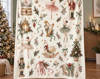 May include: A cream-colored throw blanket featuring a repeating pattern of Christmas-themed illustrations including ballerinas, nutcrackers, a swan, a harp, a snow globe, a decorated tree, ornaments, and pine branches with red berries.