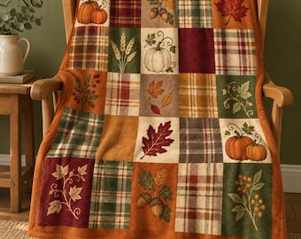 May include: A patchwork throw blanket featuring a grid of squares with autumn-themed illustrations including orange pumpkins, acorns, wheat stalks, and various fall leaves in shades of red, brown, green, and gold, interspersed with plaid patterns.