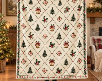 May include: A cream-colored throw blanket featuring a diamond grid pattern outlined in green vines with red berries. The pattern includes repeating illustrations of green pine trees, red poinsettia flowers, and gold bells throughout the design.