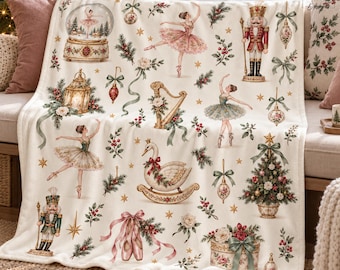 May include: A cream-colored throw blanket featuring a repeating Christmas-themed pattern of ballerinas, nutcrackers, a swan rocking horse, a harp, a snow globe, a decorated tree, ballet slippers, and festive greenery with red berries.